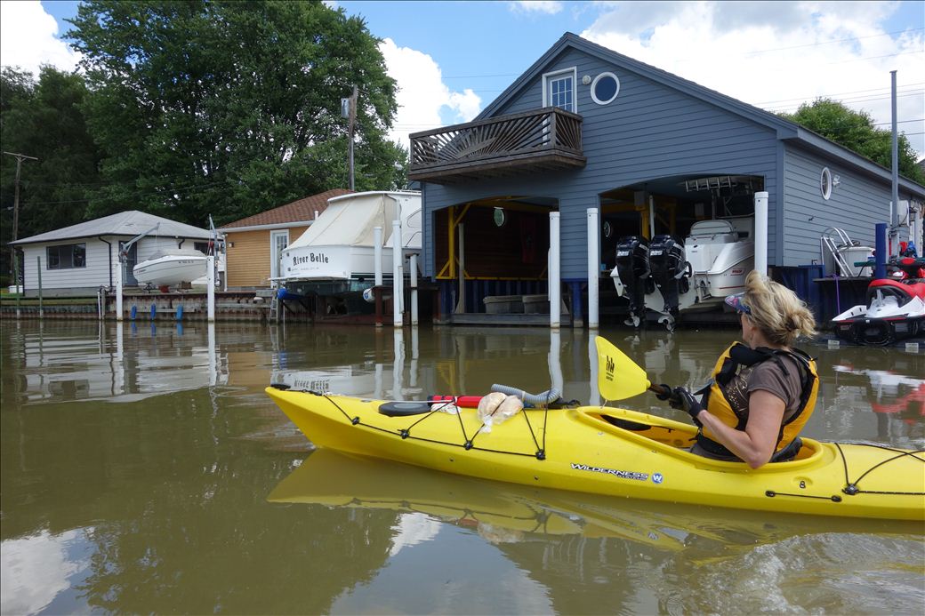 Kayakers floating past boathouses